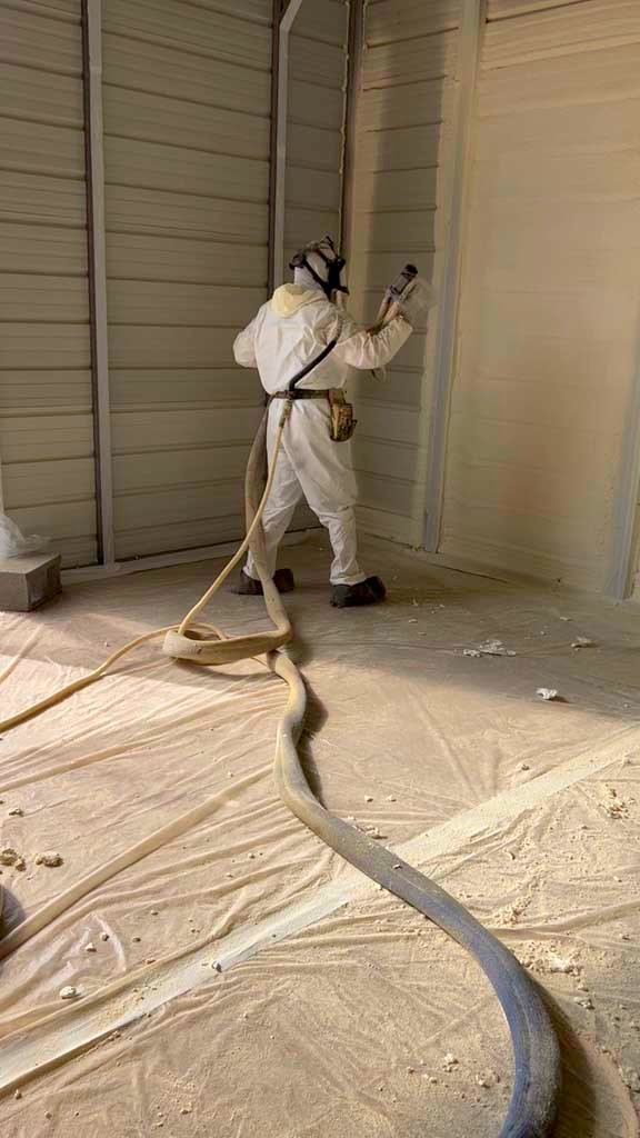 A man applying spray foam insulation to a new construction